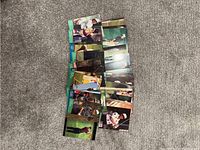 Photo showing 26 golf cards spread on carpeted floor in overlapping rows, various golfers and card designs visible.