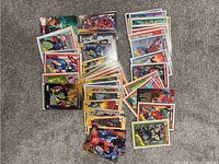 Photo showing a large assortment of Marvel trading cards spread out on a carpeted floor.