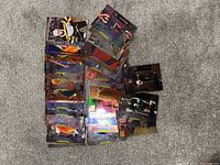 A pile of assorted Metal Universe trading cards laid out on a carpet surface, showing various artists, bands, and holographic effects on the cards.