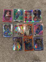 Photo of 10 assorted NBA basketball cards with colorful and holographic designs laid out on carpet.