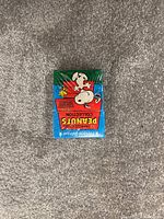 Photo of a sealed Peanuts Collection trading card pack showing Snoopy and Woodstock on the front with colorful packaging.