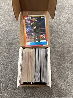 Photo of a cardboard box filled with a large number of WWE trading cards with a Triple H card on top