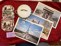 Photo of two art deco style trays with Paris street scenes, covered by three large placemats showing major Paris landmarks