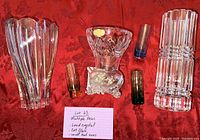 Photo showing five vases on a red cloth background including a large lead crystal vase, cut glass vase, and three small bud vases in different colors.