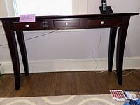 Full view of narrow wooden side table showing three drawers and legs
