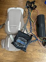 Photo shows Homedics massaging chair with wired remote, resistance bands with handles, black foam roller, and black carrying bag with text.
