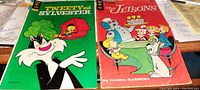 Photo of two comic books: Tweety and Sylvester on the left; The Jetsons on the right, showing front covers and condition.