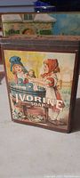 Full view of the tin showing the front panel graphics of two girls doing laundry and the Ivorine Soap brand name.