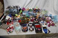 Wide view of various Playmobil toys including police vehicles, figures, accessories, and small parts spread out on surface.
