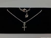 Photo showing the full necklace laid flat with the cross pendant centered and the Swarovski logo tag near the clasp.