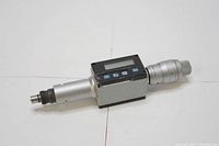 Left side angled view of the Mitutoyo digital micrometer measuring tool showing the digital LCD display, spindle, and thimble with measurement markings.
