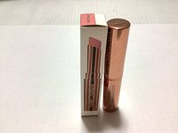 Lipstick tube placed next to a box with image, shade label, and brand text visible.