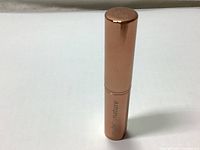 Full view of rose gold concealer tube with branding visible