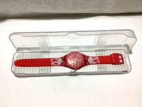 Red Swatch watch with custom Lindt Lindor chocolate wrapper design strap inside clear plastic case.