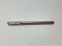 Photo of the full lip pencil with sealed cap showing the berry color end and barcode sticker on the opposite end.