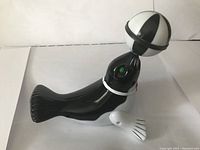 Front view of the black and white acrobatic seal holding a ball on its nose, showing detail of the toy's design and colors.