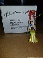 Photo of Snow White Christmas tree ornament with its original box showing product information and branding