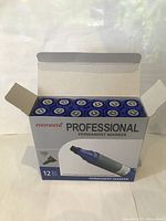 Opened box showing 12 blue Monami Professional permanent markers with caps on.