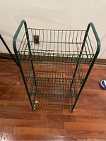 Front view of green metal rolling rack showing three wire mesh shelves and frame.