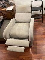 Front view of the light grey recliner chair with footrest extended, showing padded armrests, thick seat cushion, and backrest with head support.