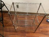 Front perspective view showing the full rack with three wire shelves and adjustable shelf levels.