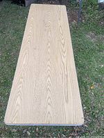 Top view of the table showing light wood grain laminate surface, rectangular shape with rounded corners.