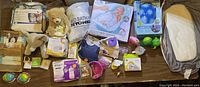 Overview photo showing assortment of baby supplies including stuffed animals, feeding bottles, changing pad, packaged baby goods, and small toys.