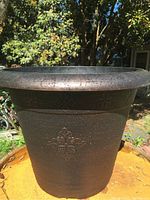 Image shows a large plastic planter pot with textured copper finish, decorative patterns on the upper section, and rounded shape.