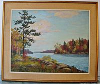 Framed oil painting of a waterscene with treed shoreline and rocks in the foreground, signed by Alice Switzer.