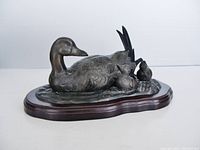 Side angle showing the duck and ducklings detail on bronze cast sculpture with wood base.
