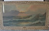 Full view of the oil on canvas seascape painting showing ocean waves, rocky coastline, sky, and decorative frame.