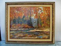 Full view of the M. Booth oil painting showing fall foliage and ducks flying over a water body in the natural scene. The frame is visible with some wear.