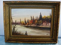 Frontal view of the framed oil painting showing lake and tree scene with autumn colors