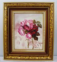 Frontal photo of the framed oil painting showing pink and red roses on board, with signature visible.
