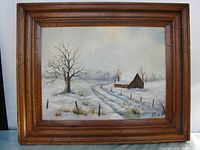 Full frontal view of the signed oil painting in original wooden frame showing the winter barn scene with tree, path, and snow.