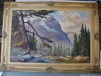 Framed oil mountain landscape painting showing full view including decorative frame.