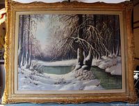 Frontal view of the framed oil painting depicting a snow-covered winter landscape with trees and a stream, showing the signature and frame details.