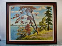Framed oil painting of a fall lake landscape showing trees with autumn foliage and a lake with hills in the background.