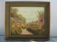 Frontal view of framed oil painting showing thatched roof cottage and garden pathway, signed WJ Davis in lower right corner
