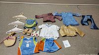 Full set of American Girl doll clothing and accessories laid out on floor, showing various outfits, shoes, and accessories.