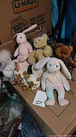 Overview of the lot with 8 Ty Beanie Babies including pink rabbit, yellow bear, white unicorn, brown bear, pastel rabbit, and two dogs.