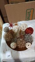 Overview of assorted Christmas sparkly decorative items on a round tray including glittery cones, wire and rattan balls, and star ornaments.