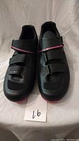 Front view of Izumi bike shoes showing black body with pink accent and three Velcro straps closing.