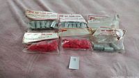 Photo showing seven sealed packs of Kover Klamps boat framing system components including steel couplings, end plugs, and rubber tips on a light fabric background.