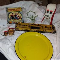 Lot contents with vintage boxed toy, rifle cleaning rod, owl figurine, ceramic dish, plush dog, and yellow enamel plate.