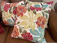Five square floral outdoor pillows arranged on a couch showing colorful design and condition