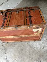 Side and top view of the vintage leather trunk showing leather panels, wooden framing, and metal hardware.