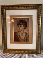 Framed needle point artwork of a woman's portrait, showing the entire frame and artwork inside.