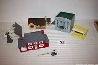 Photo of the four Plasticville structures together showing their size and condition on a striped cloth.