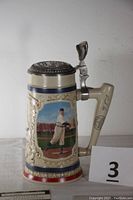 Front view showing Cy Young image and intricate sculpted border on a ceramic stein with hinged metal lid